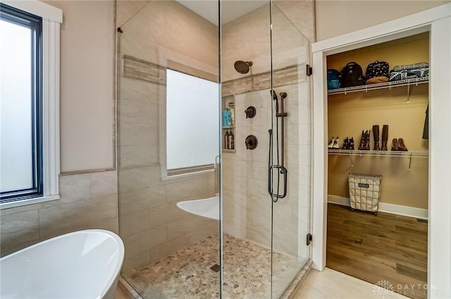 bathroom featuring hardwood / wood-style flooring, shower with separate bathtub, and tile walls