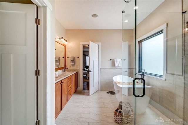 bathroom with vanity, shower with separate bathtub, and tile walls