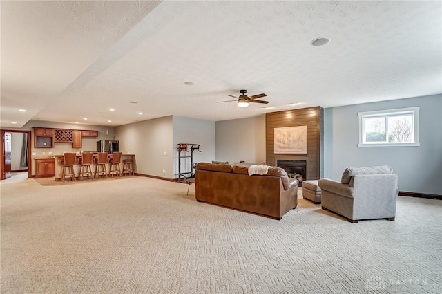 carpeted living room featuring ceiling fan, indoor bar, a fireplace, and a textured ceiling