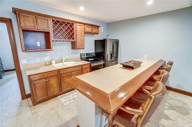 kitchen featuring stainless steel appliances, sink, light tile patterned floors, and a breakfast bar