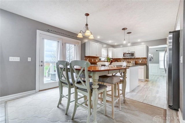 dining area with light hardwood / wood-style floors and a textured ceiling