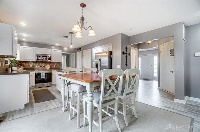 kitchen with tasteful backsplash, a center island, hanging light fixtures, appliances with stainless steel finishes, and white cabinets