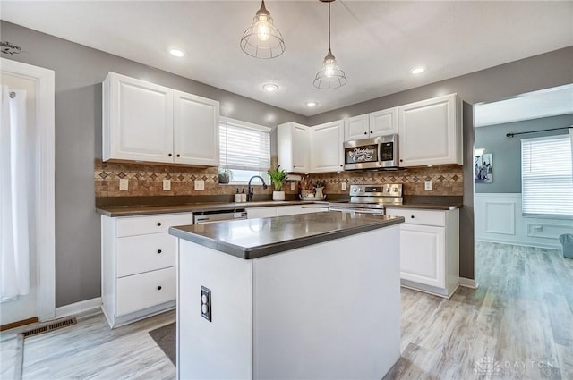 kitchen featuring hanging light fixtures, white cabinetry, appliances with stainless steel finishes, and a center island