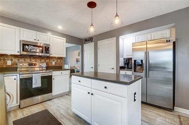 kitchen with pendant lighting, appliances with stainless steel finishes, white cabinetry, tasteful backsplash, and a kitchen island