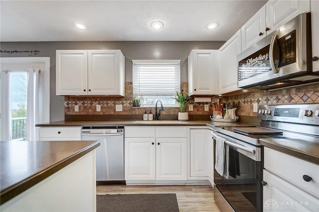 kitchen featuring sink, backsplash, white cabinets, light hardwood / wood-style floors, and stainless steel appliances