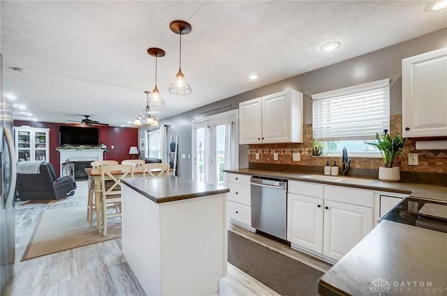 kitchen with sink, dishwasher, white cabinets, pendant lighting, and backsplash