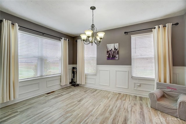 unfurnished dining area featuring a notable chandelier and light hardwood / wood-style flooring