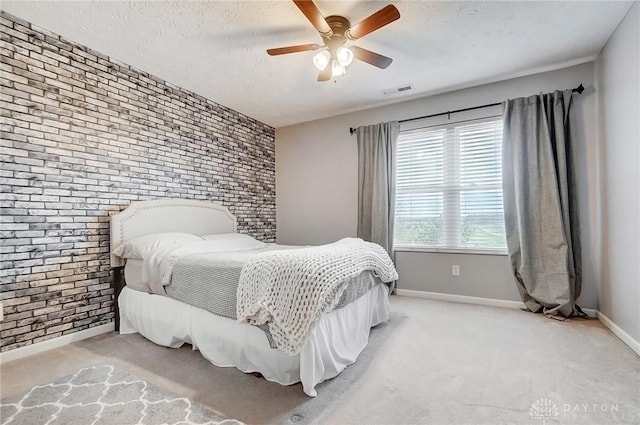 bedroom with ceiling fan, light colored carpet, a textured ceiling, and brick wall