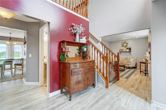 staircase featuring wood-type flooring, a high ceiling, and a notable chandelier