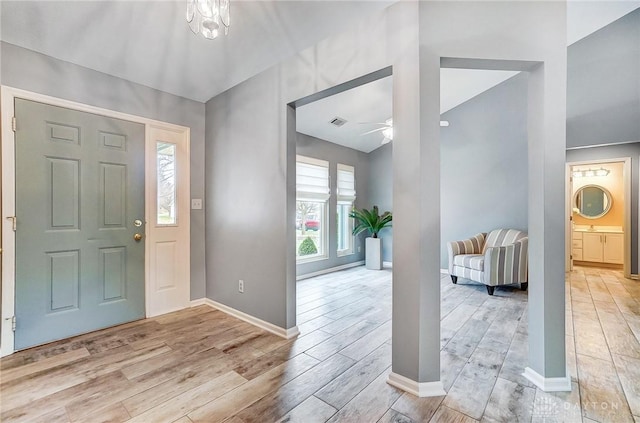 entrance foyer featuring ceiling fan with notable chandelier and light hardwood / wood-style flooring