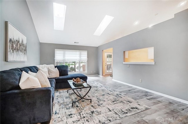 living room with vaulted ceiling with skylight and light hardwood / wood-style floors