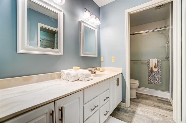 bathroom with vanity, hardwood / wood-style floors, an enclosed shower, and toilet