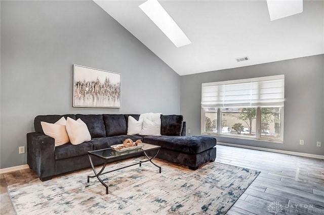 living room with high vaulted ceiling, a skylight, and light hardwood / wood-style floors