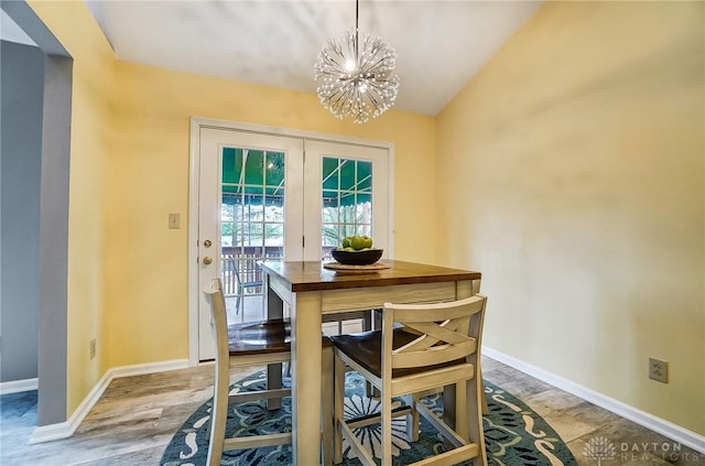 dining room with vaulted ceiling, an inviting chandelier, and light wood-type flooring