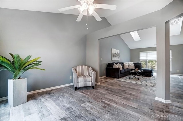 living area featuring lofted ceiling with skylight, wood-type flooring, and ceiling fan