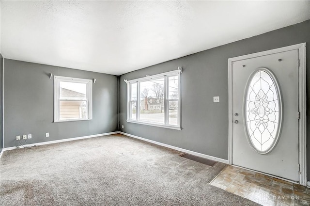 foyer entrance featuring dark carpet