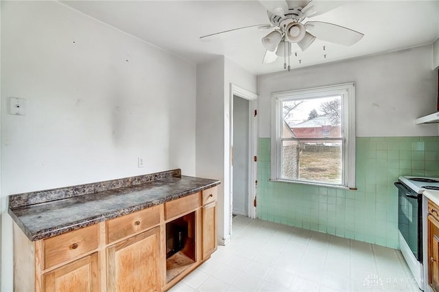 kitchen with electric stove, ceiling fan, and tile walls