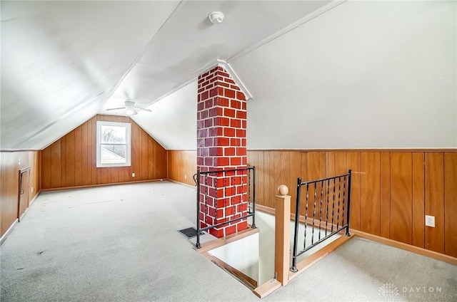 additional living space featuring light colored carpet, wooden walls, and vaulted ceiling