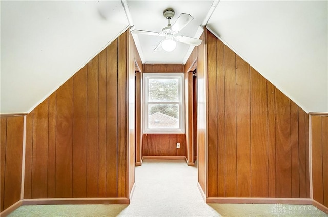 additional living space with ceiling fan, light carpet, and wooden walls