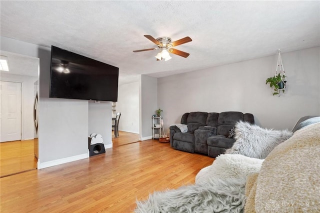 living room featuring hardwood / wood-style flooring, ceiling fan, and a textured ceiling