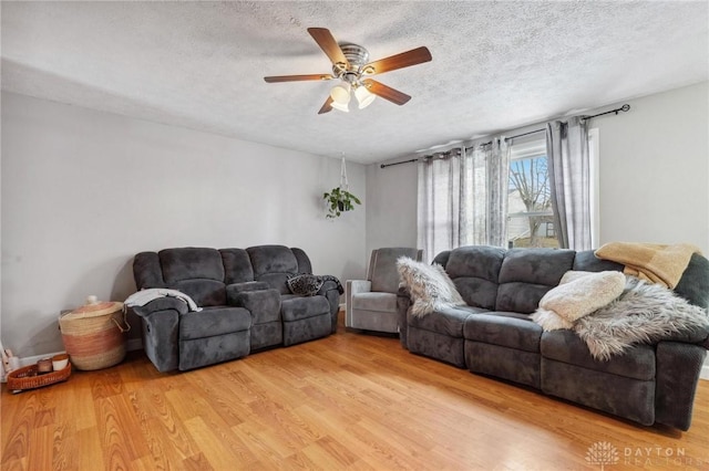 living room with ceiling fan, light hardwood / wood-style floors, and a textured ceiling