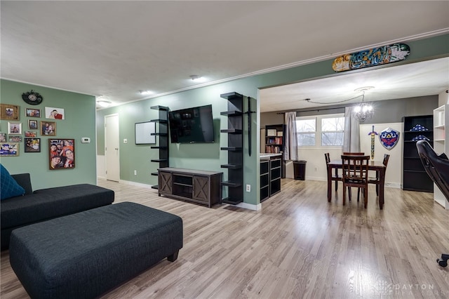 living room with ornamental molding, wood-type flooring, and a chandelier