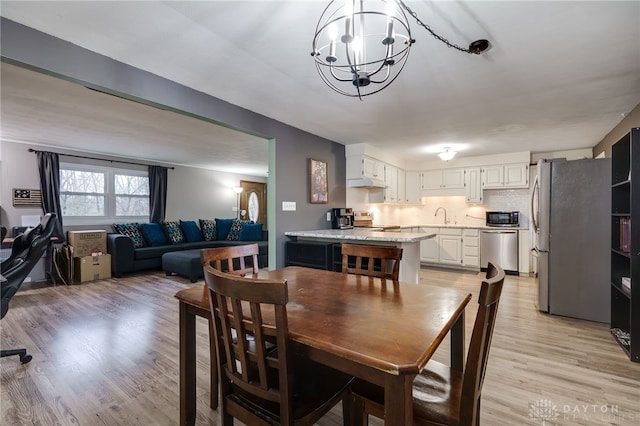 dining space featuring a chandelier, sink, and light hardwood / wood-style flooring