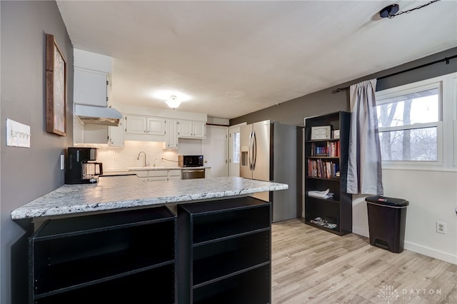 kitchen with kitchen peninsula, white cabinets, decorative backsplash, stainless steel fridge with ice dispenser, and light wood-type flooring