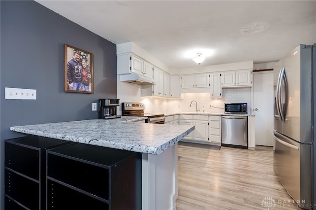 kitchen with sink, white cabinetry, stainless steel appliances, light hardwood / wood-style floors, and kitchen peninsula