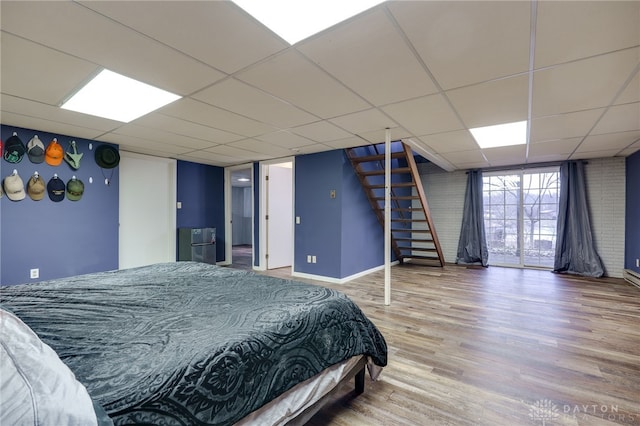 bedroom with a drop ceiling, hardwood / wood-style flooring, and expansive windows