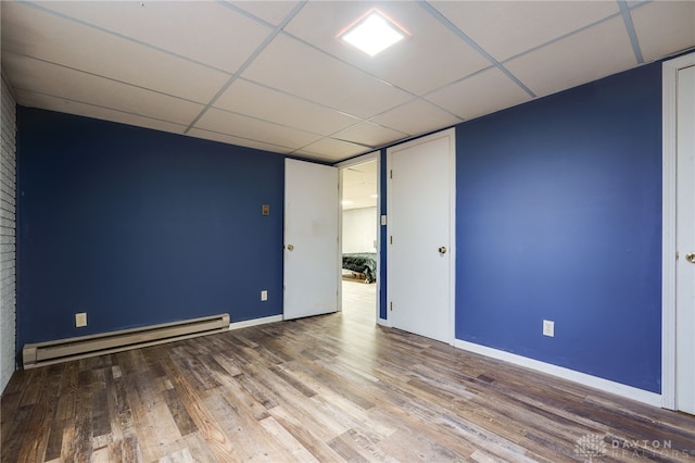 spare room with hardwood / wood-style floors, a drop ceiling, and baseboard heating