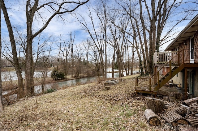 view of yard featuring a deck with water view and an outdoor fire pit