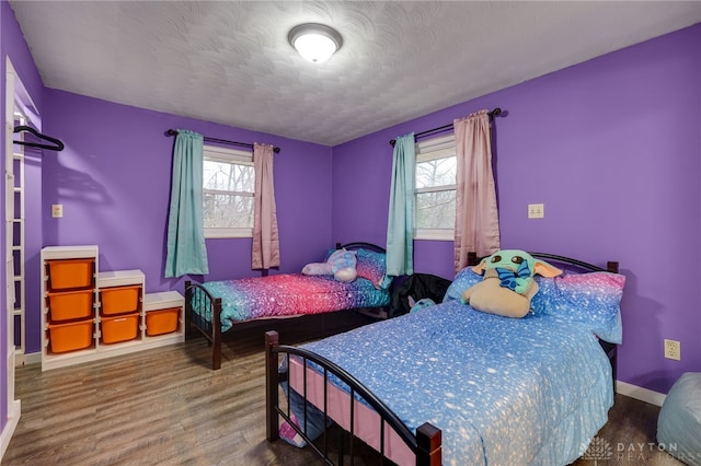 bedroom featuring multiple windows, wood-type flooring, and a textured ceiling