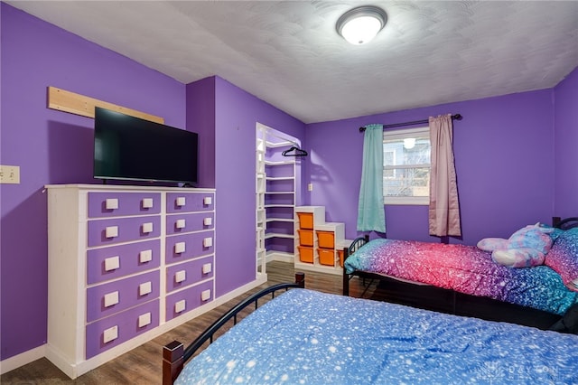 bedroom featuring hardwood / wood-style floors, a spacious closet, and a textured ceiling