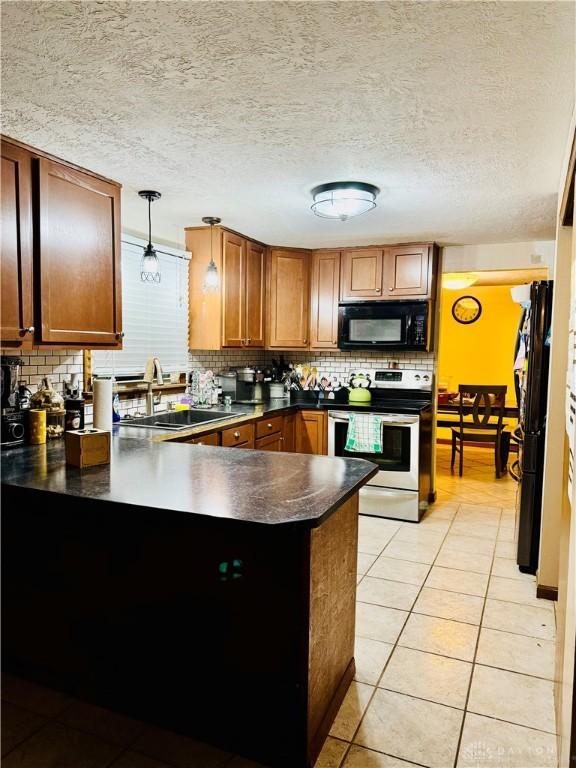 kitchen with pendant lighting, sink, light tile patterned floors, black appliances, and kitchen peninsula