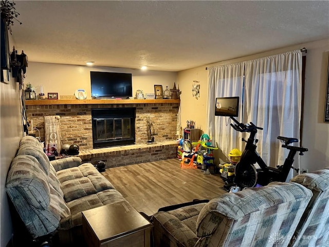 living room featuring wood-type flooring and a brick fireplace