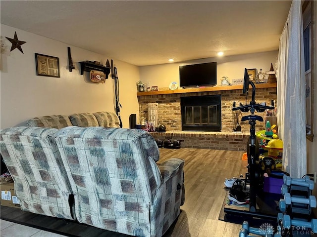 living room with brick wall, a fireplace, and light hardwood / wood-style floors