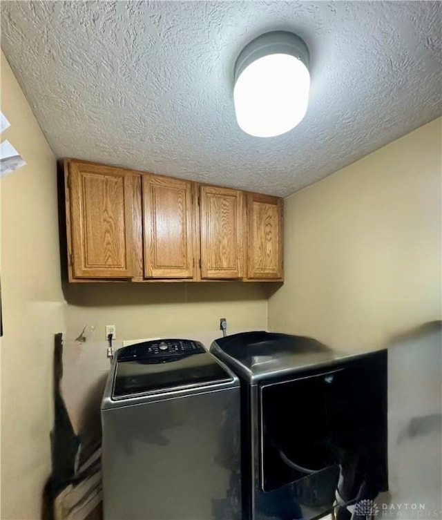 washroom with cabinets, washing machine and dryer, and a textured ceiling