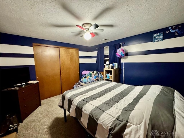 carpeted bedroom with ceiling fan, a closet, and a textured ceiling