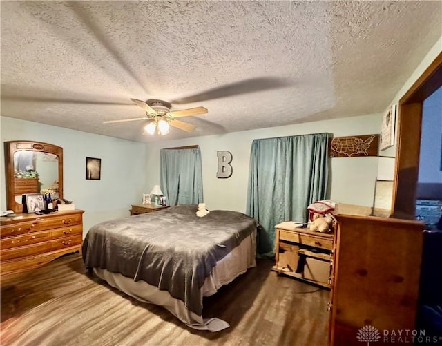 bedroom featuring hardwood / wood-style floors, a textured ceiling, and ceiling fan