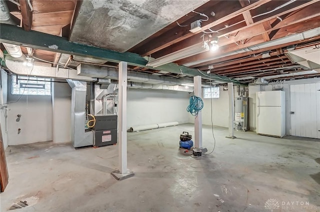 basement with heating unit, water heater, and white fridge