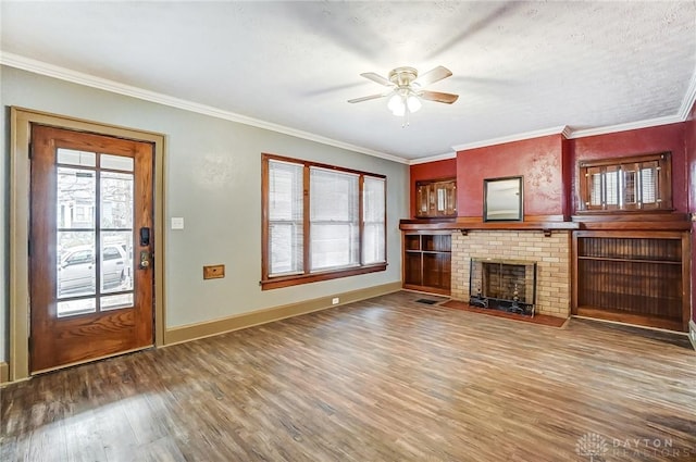 unfurnished living room with ornamental molding, hardwood / wood-style floors, ceiling fan, and a fireplace