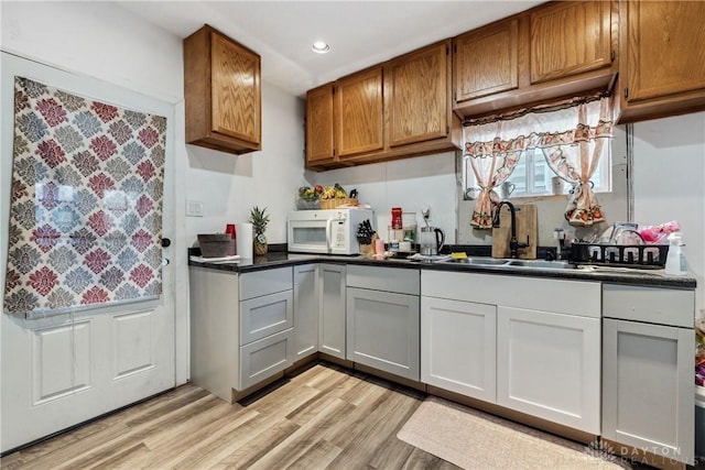 kitchen with white cabinetry, sink, and light hardwood / wood-style flooring