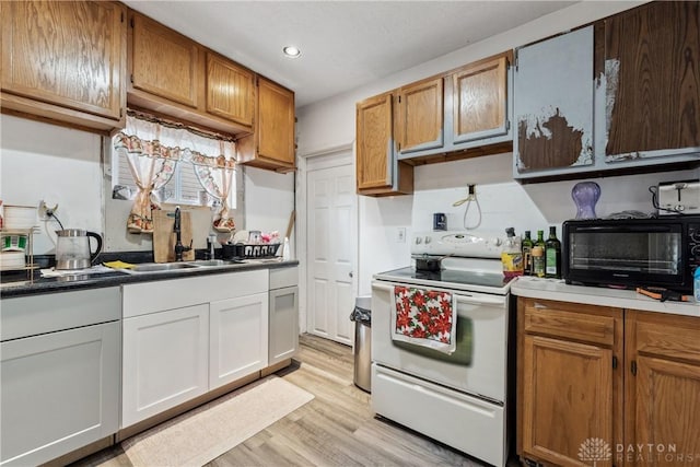 kitchen with electric stove, sink, light hardwood / wood-style flooring, and white cabinets