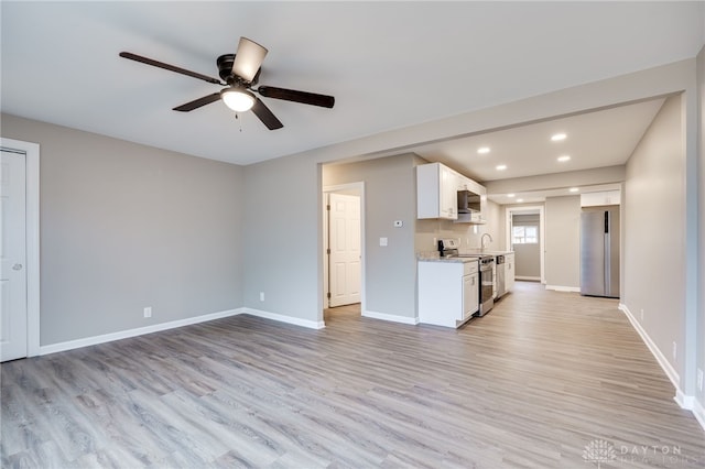 kitchen featuring appliances with stainless steel finishes, white cabinetry, sink, light stone counters, and light hardwood / wood-style floors