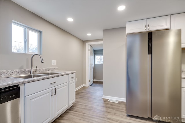 kitchen with sink, stainless steel appliances, white cabinets, and light wood-type flooring