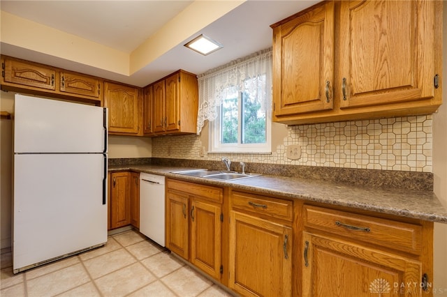 kitchen with white appliances, a sink, brown cabinets, decorative backsplash, and dark countertops