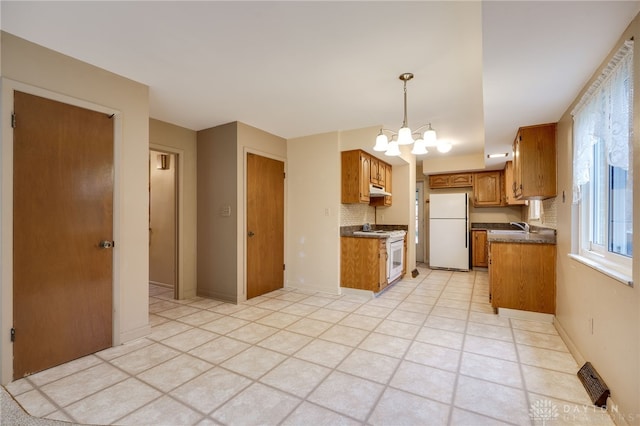 kitchen with brown cabinets, a notable chandelier, dark countertops, visible vents, and freestanding refrigerator