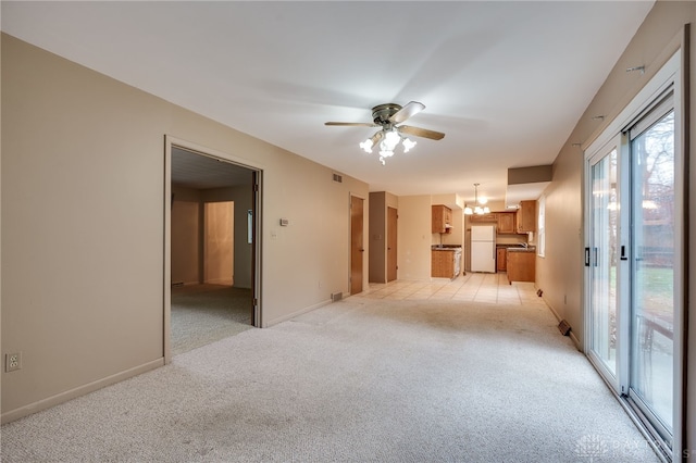 unfurnished room featuring light carpet, ceiling fan with notable chandelier, visible vents, and baseboards