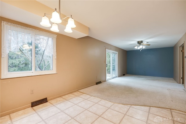 empty room with ceiling fan with notable chandelier, light carpet, visible vents, and baseboards